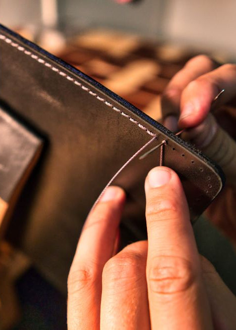 Person working on a leather product with a focus on craftsmanship
